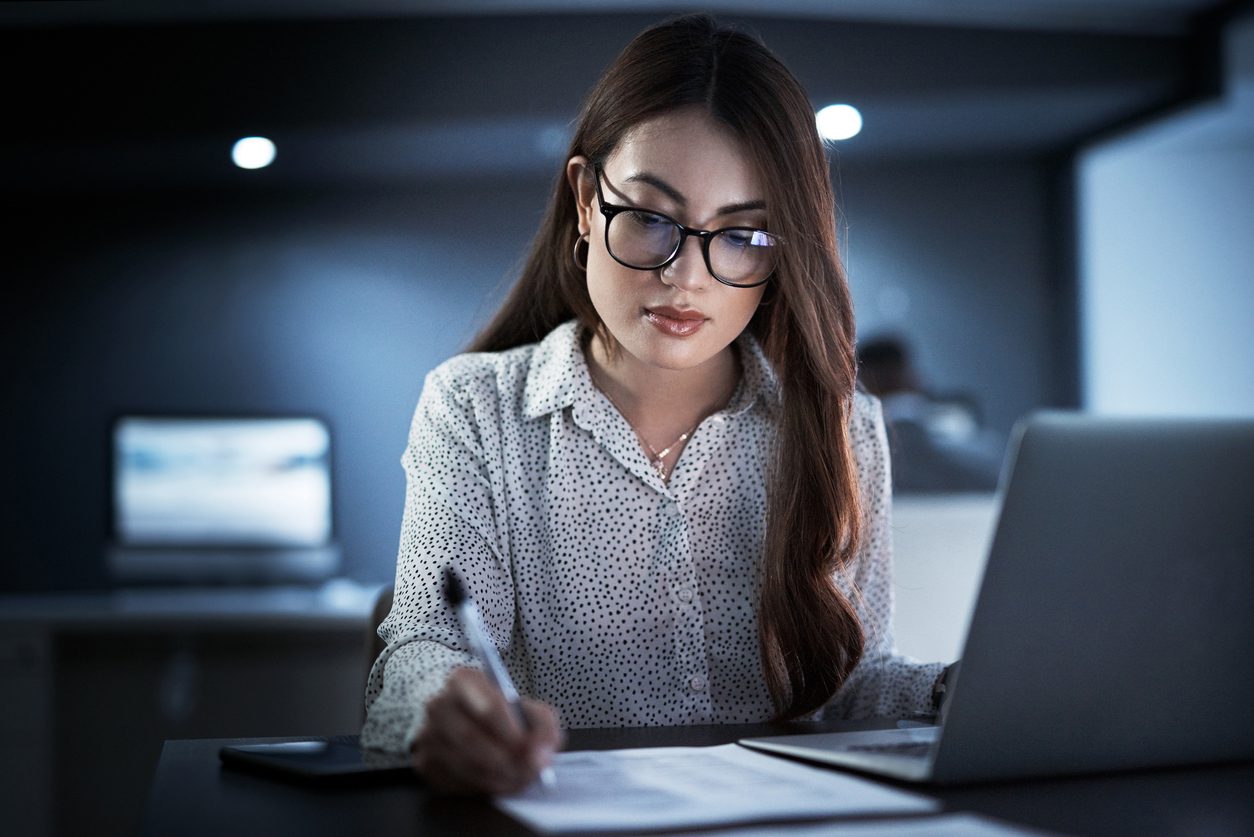 A young woman sits at her desk, getting her paperwork in order